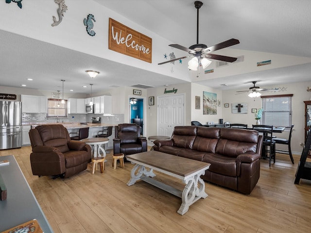 living area with light wood-type flooring, ceiling fan, visible vents, and lofted ceiling