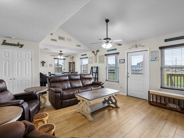 living area featuring light wood-type flooring, visible vents, plenty of natural light, and lofted ceiling