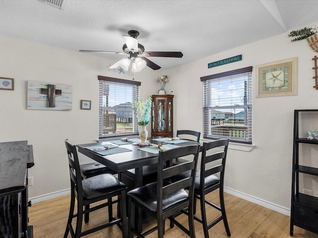 dining room with ceiling fan, a textured ceiling, light hardwood / wood-style flooring, and a wealth of natural light