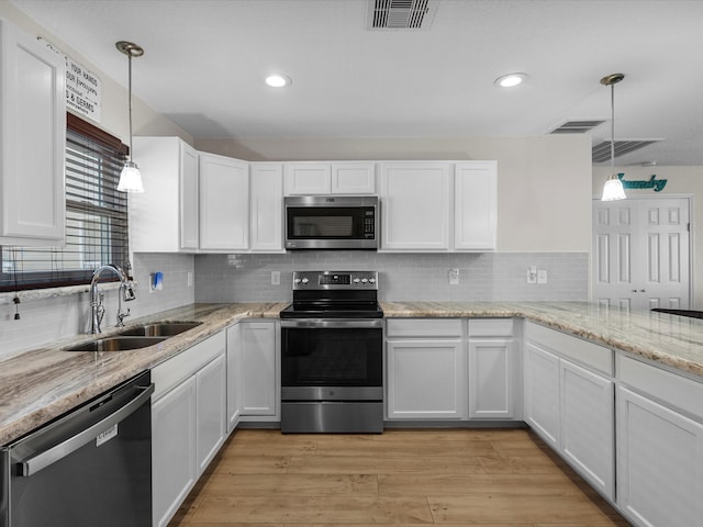 kitchen featuring stainless steel appliances, white cabinets, decorative light fixtures, and sink