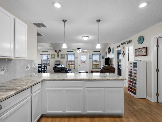 kitchen with ceiling fan, light wood-type flooring, kitchen peninsula, and white cabinetry