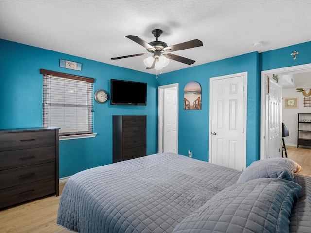 bedroom with a textured ceiling, light hardwood / wood-style floors, and ceiling fan