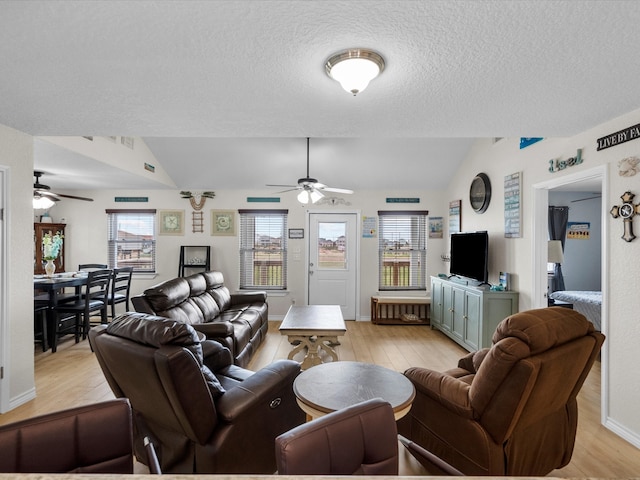 living area featuring light wood-style floors, lofted ceiling, ceiling fan, and a textured ceiling