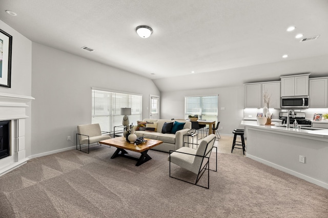 carpeted living room featuring lofted ceiling and sink