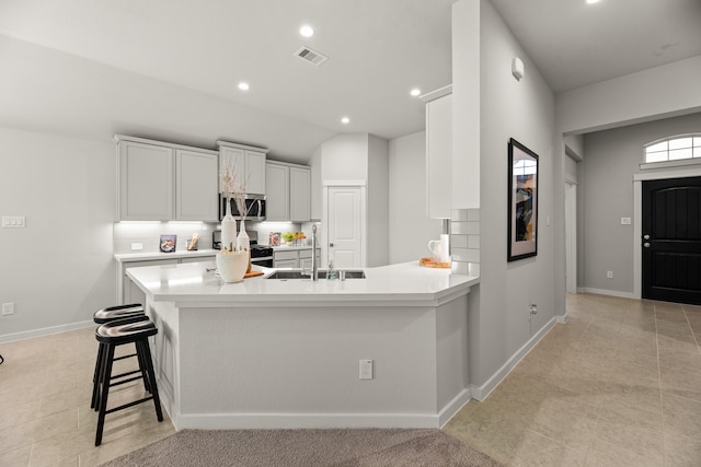 kitchen with a breakfast bar, sink, white cabinetry, kitchen peninsula, and stainless steel appliances