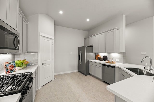 kitchen with light tile patterned floors, sink, tasteful backsplash, gray cabinetry, and stainless steel appliances