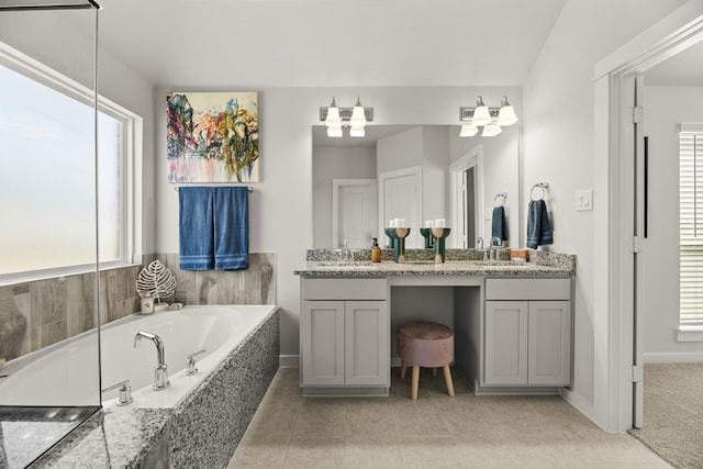 bathroom with tiled tub, vanity, tile patterned floors, and a wealth of natural light