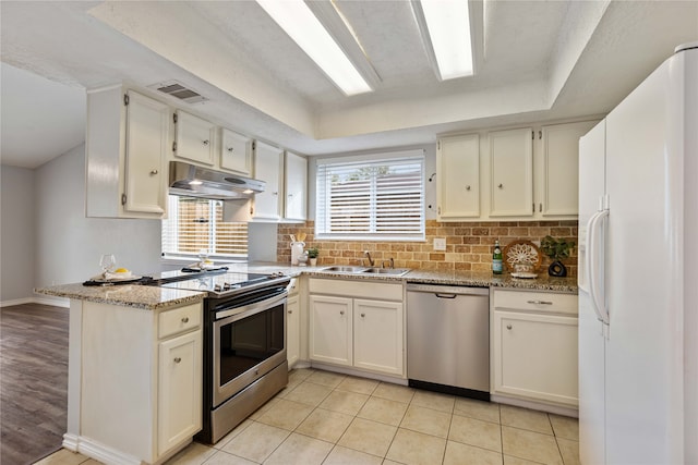 kitchen with tasteful backsplash, light hardwood / wood-style floors, stainless steel appliances, sink, and light stone counters