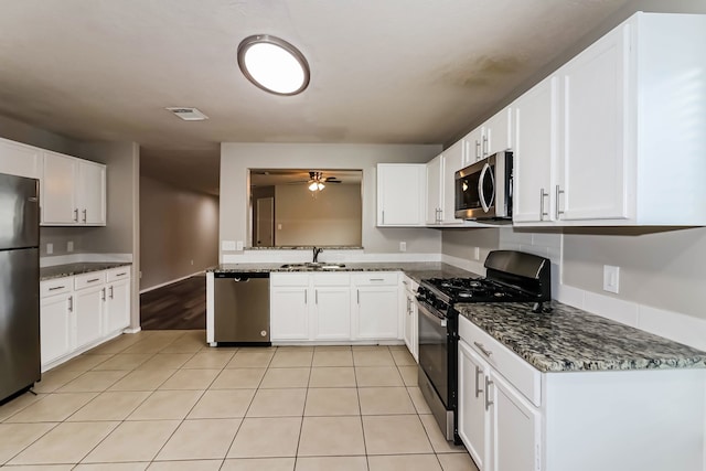 kitchen with dark stone counters, light tile patterned floors, stainless steel appliances, ceiling fan, and white cabinets