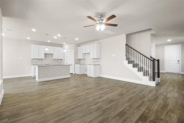 unfurnished living room with dark wood-style floors, baseboards, recessed lighting, ceiling fan, and stairs