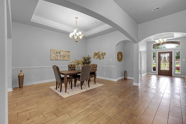 dining room with light hardwood / wood-style flooring, a tray ceiling, an inviting chandelier, and crown molding