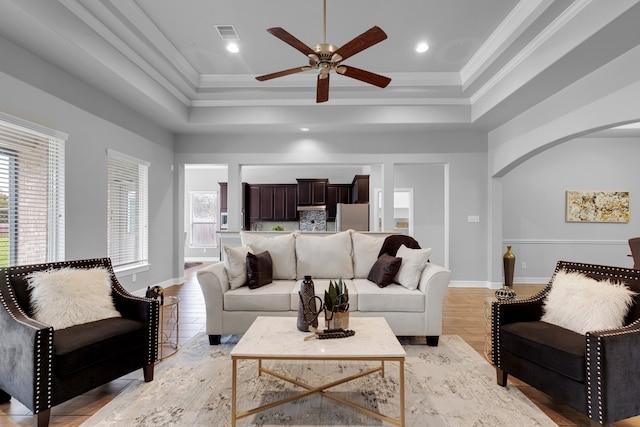 living room featuring light hardwood / wood-style floors, ornamental molding, and a tray ceiling