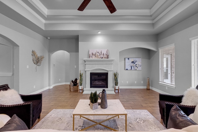 living room featuring a tray ceiling, light hardwood / wood-style floors, ceiling fan, and crown molding