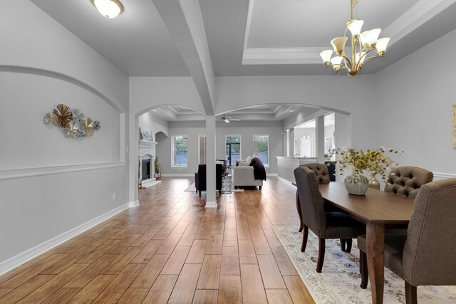 dining room with ceiling fan with notable chandelier, light hardwood / wood-style floors, a raised ceiling, and ornamental molding