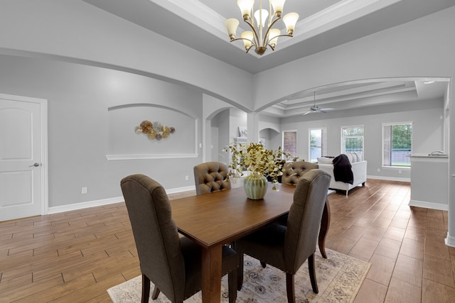 dining room with ceiling fan with notable chandelier, a tray ceiling, and ornamental molding