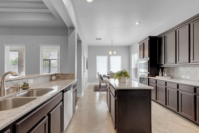 kitchen with appliances with stainless steel finishes, sink, light stone counters, and a wealth of natural light