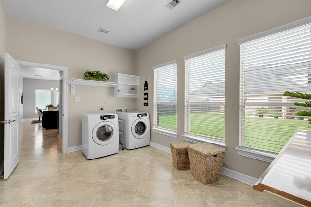 laundry room with an inviting chandelier, light tile patterned floors, and washing machine and dryer