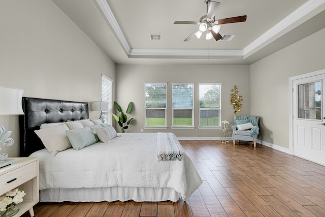 bedroom with wood-type flooring, a tray ceiling, ceiling fan, and crown molding