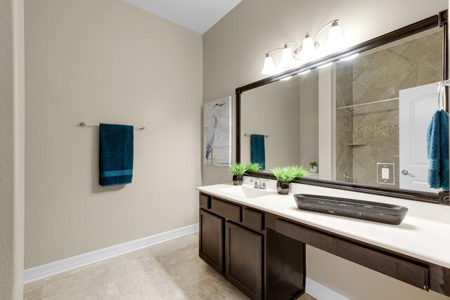 bathroom with tiled shower, vanity, and tile patterned floors