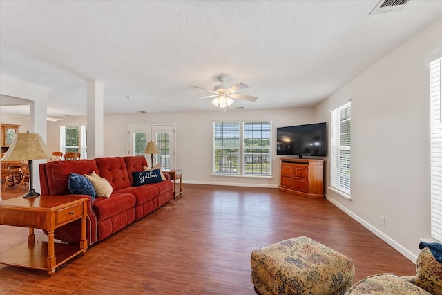 living room with a textured ceiling, ceiling fan, and dark wood-type flooring