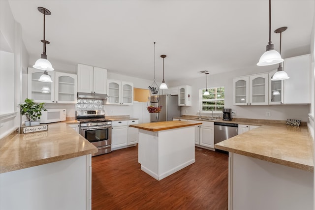 kitchen featuring appliances with stainless steel finishes, dark wood-type flooring, white cabinets, a center island, and butcher block countertops