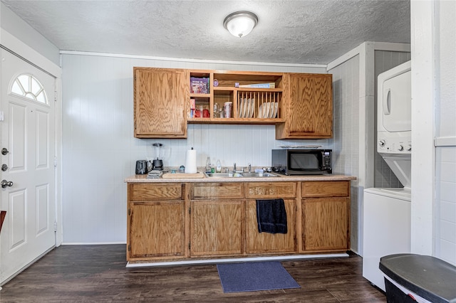 kitchen featuring dark wood-type flooring, stacked washer and clothes dryer, a textured ceiling, and sink