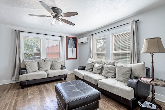 living room with dark wood-type flooring, ceiling fan, an AC wall unit, and a textured ceiling