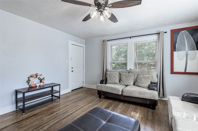 living room featuring dark hardwood / wood-style flooring, ceiling fan, and a textured ceiling