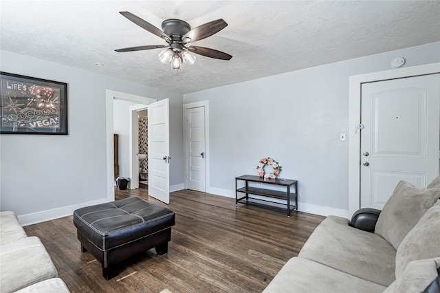 living room featuring dark wood-type flooring, ceiling fan, and a textured ceiling