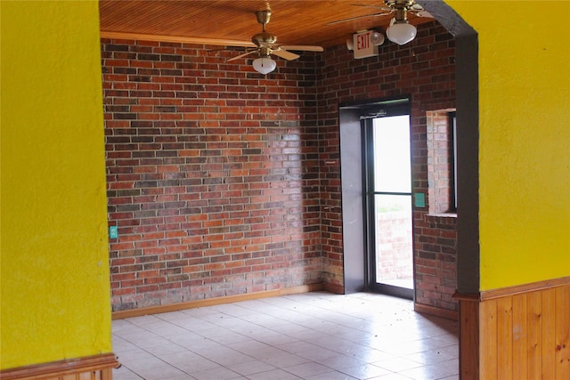 tiled spare room with wooden ceiling, brick wall, ceiling fan, and wooden walls