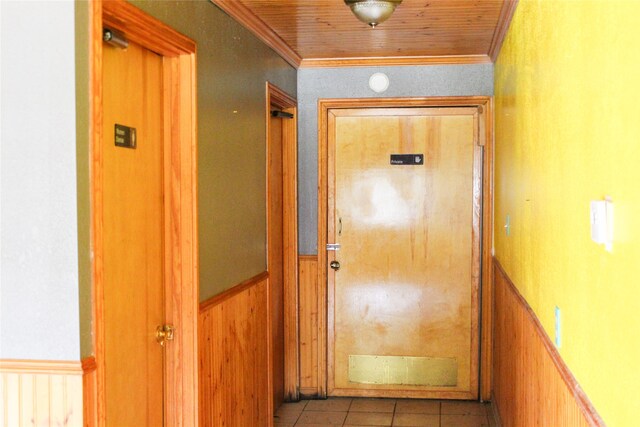 hall featuring crown molding, wood ceiling, wood walls, and light tile patterned flooring