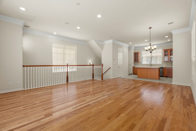 unfurnished living room featuring light hardwood / wood-style flooring, a healthy amount of sunlight, ornamental molding, and a chandelier