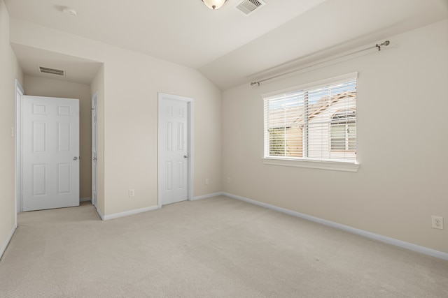 unfurnished bedroom featuring light colored carpet and vaulted ceiling