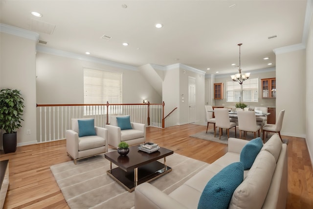 living room featuring light wood-type flooring, ornamental molding, plenty of natural light, and an inviting chandelier