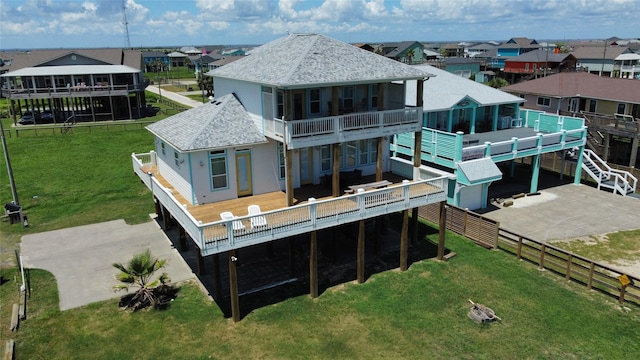 rear view of property with a yard, a shingled roof, a balcony, a residential view, and a fenced backyard