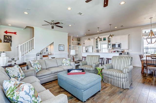 living room with dark wood-style floors, stairs, visible vents, and ornamental molding