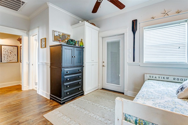 bedroom with baseboards, light wood-type flooring, visible vents, and crown molding