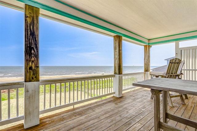 wooden terrace featuring a water view and a beach view