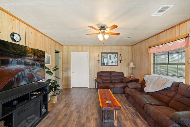 living room featuring crown molding, dark wood-type flooring, wood walls, and ceiling fan