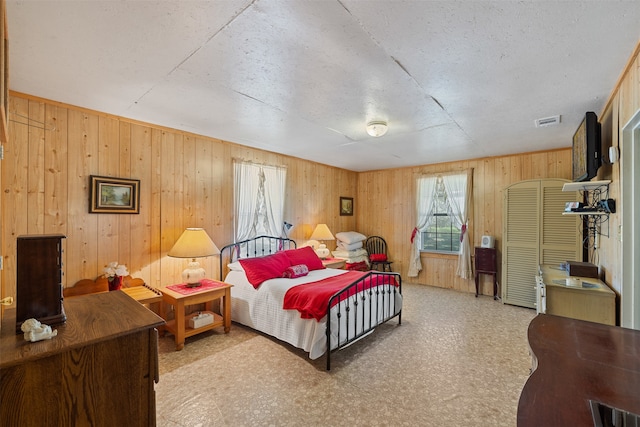 bedroom featuring a textured ceiling and wooden walls