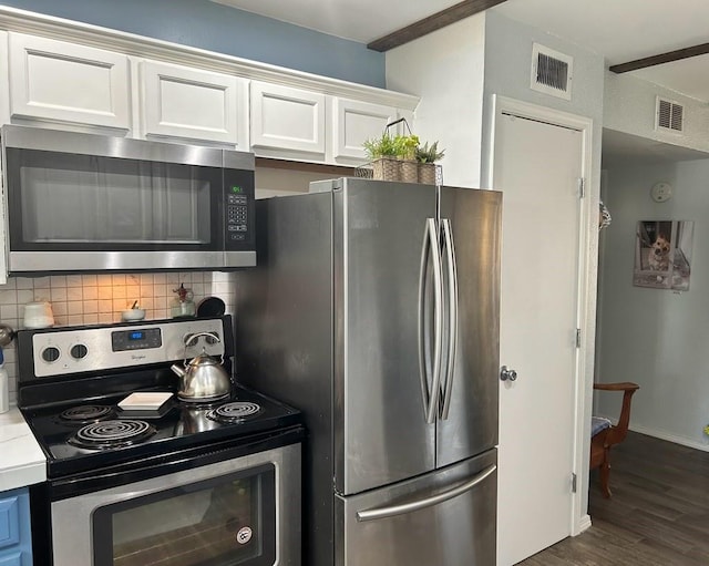 kitchen with tasteful backsplash, white cabinetry, dark wood-type flooring, and appliances with stainless steel finishes