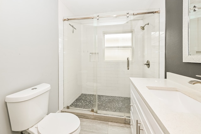 bathroom with toilet, a shower with door, and vanity