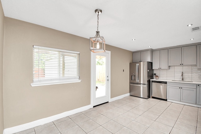 kitchen with pendant lighting, tasteful backsplash, light tile patterned floors, stainless steel appliances, and sink