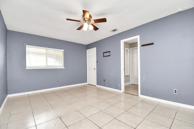 unfurnished room featuring a textured ceiling, light tile patterned floors, and ceiling fan