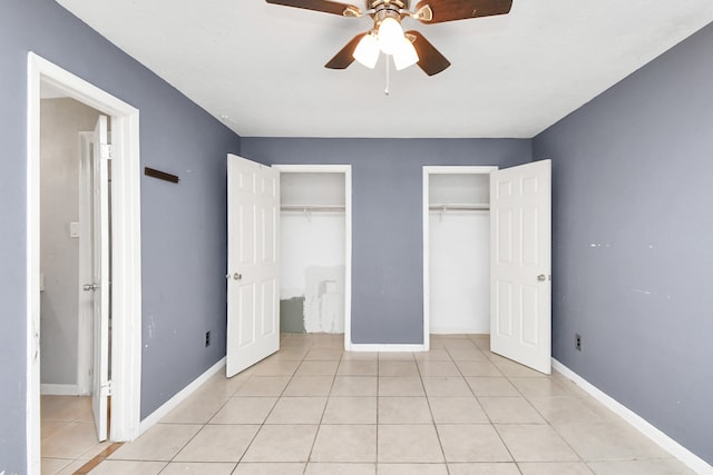 unfurnished bedroom with ceiling fan, light tile patterned floors, and two closets