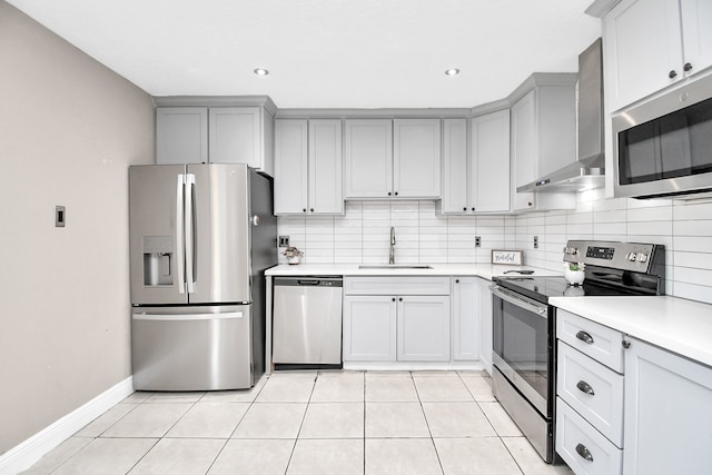 kitchen with light tile patterned floors, appliances with stainless steel finishes, sink, wall chimney range hood, and tasteful backsplash