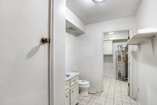 bathroom with vanity, toilet, tile patterned floors, and water heater