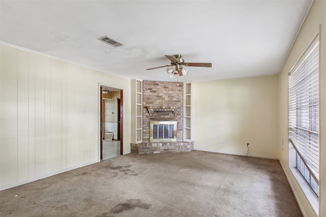 unfurnished living room featuring a fireplace, carpet floors, built in features, ceiling fan, and wooden walls