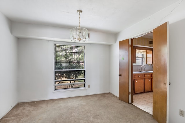 carpeted spare room with plenty of natural light, a chandelier, and sink