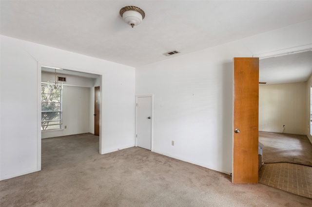 carpeted empty room with an inviting chandelier